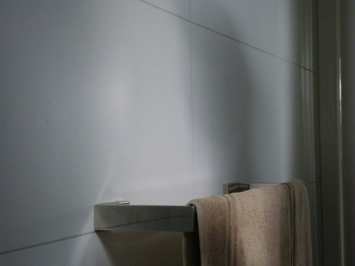 Beige towel hanging on a rack in a tiled bathroom