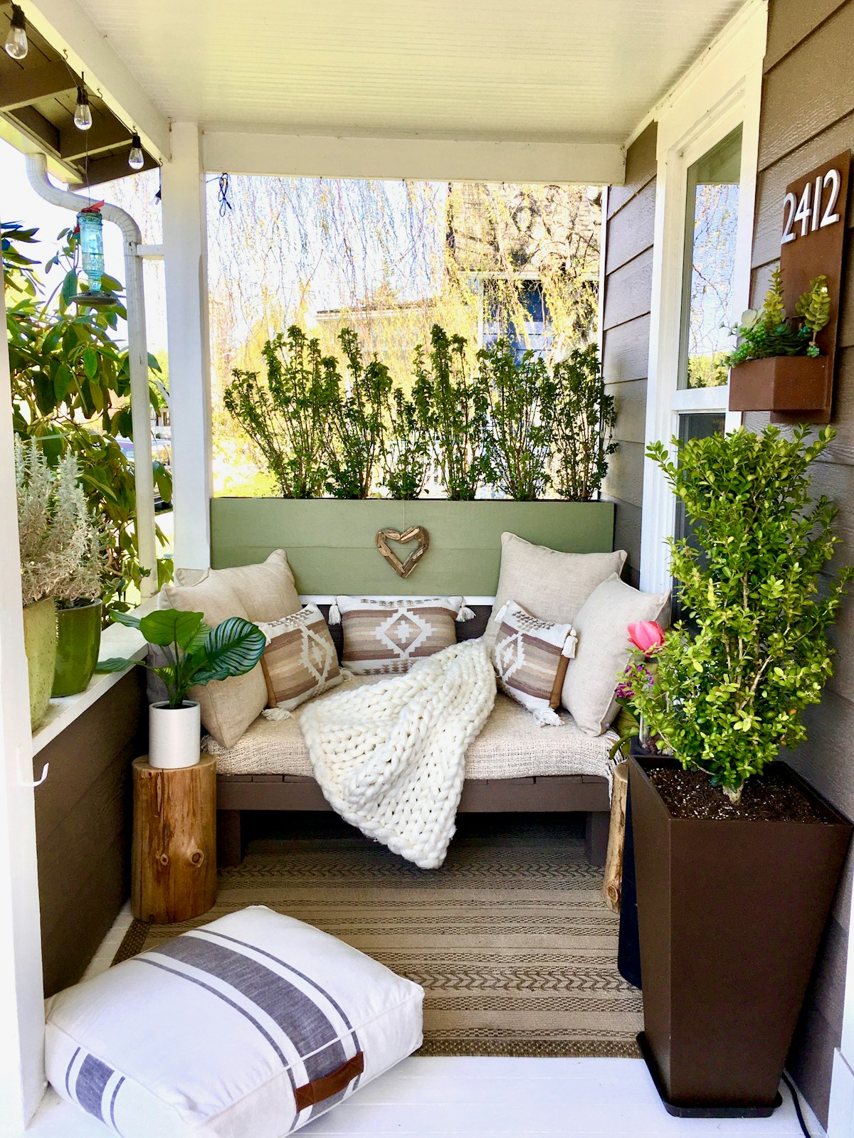 Porch bench with cushions and potted plants by the door