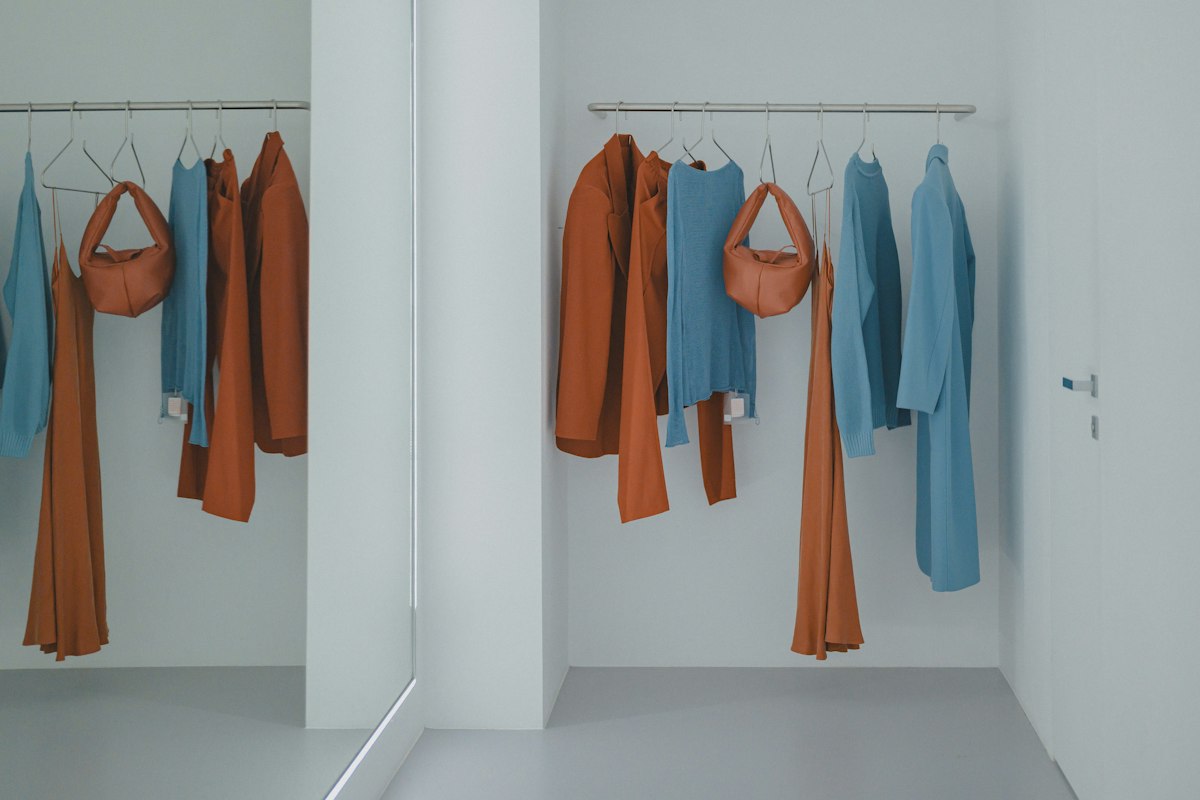 Clothes neatly hung on racks in a small white closet