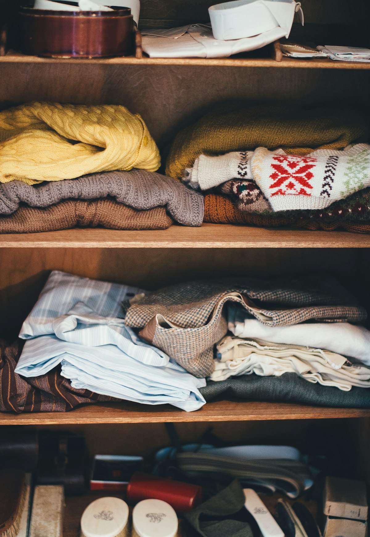 Folded sweaters and linens stacked on closet shelves