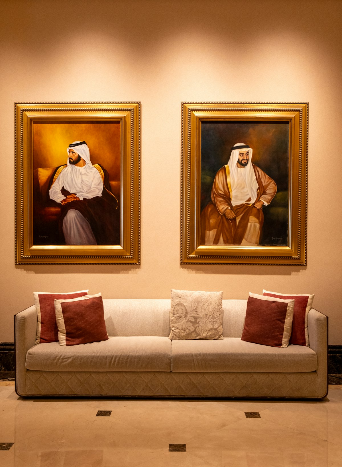 Two framed portraits hanging above a sofa in a warm living room